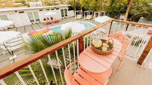 A rooftop pool area with a wooden deck, white umbrellas, and outdoor seating.