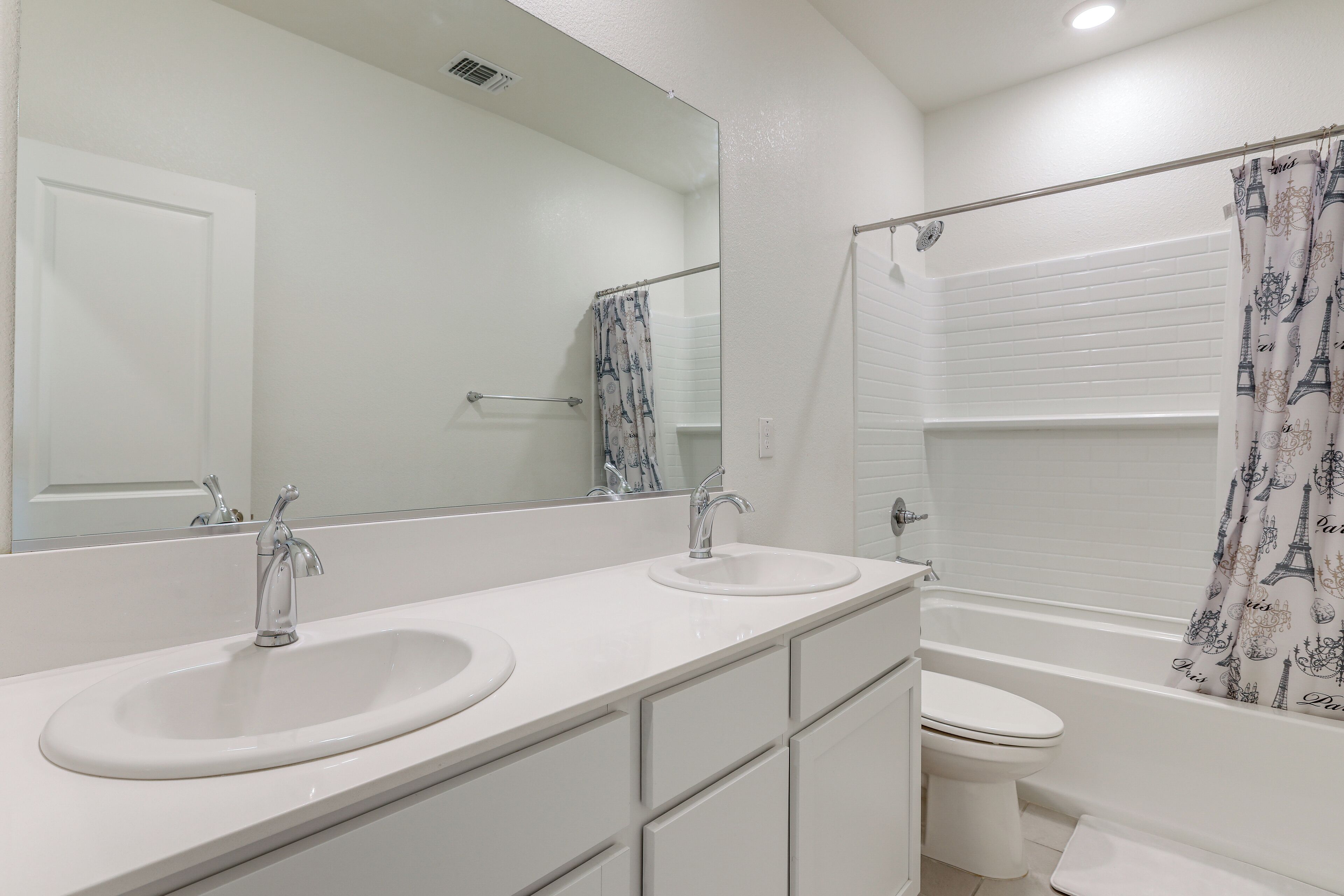 Une salle de bain avec deux éviers, des toilettes et une douche avec un rideau.