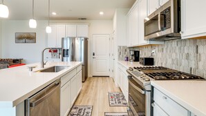 A modern kitchen with white cabinets, stainless steel appliances, and pendant lighting. - Modern Family Home in Suburbs of Sacramento! (Roseville)