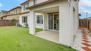 A residential building with a covered patio, a lawn, and a wooden fence. - Modern Family Home in Suburbs of Sacramento! (Roseville)