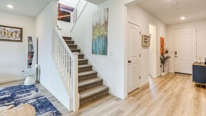 A staircase with a white railing leading to a landing, a blue patterned rug, and a wooden floor. - Modern Family Home in Suburbs of Sacramento! (Roseville)