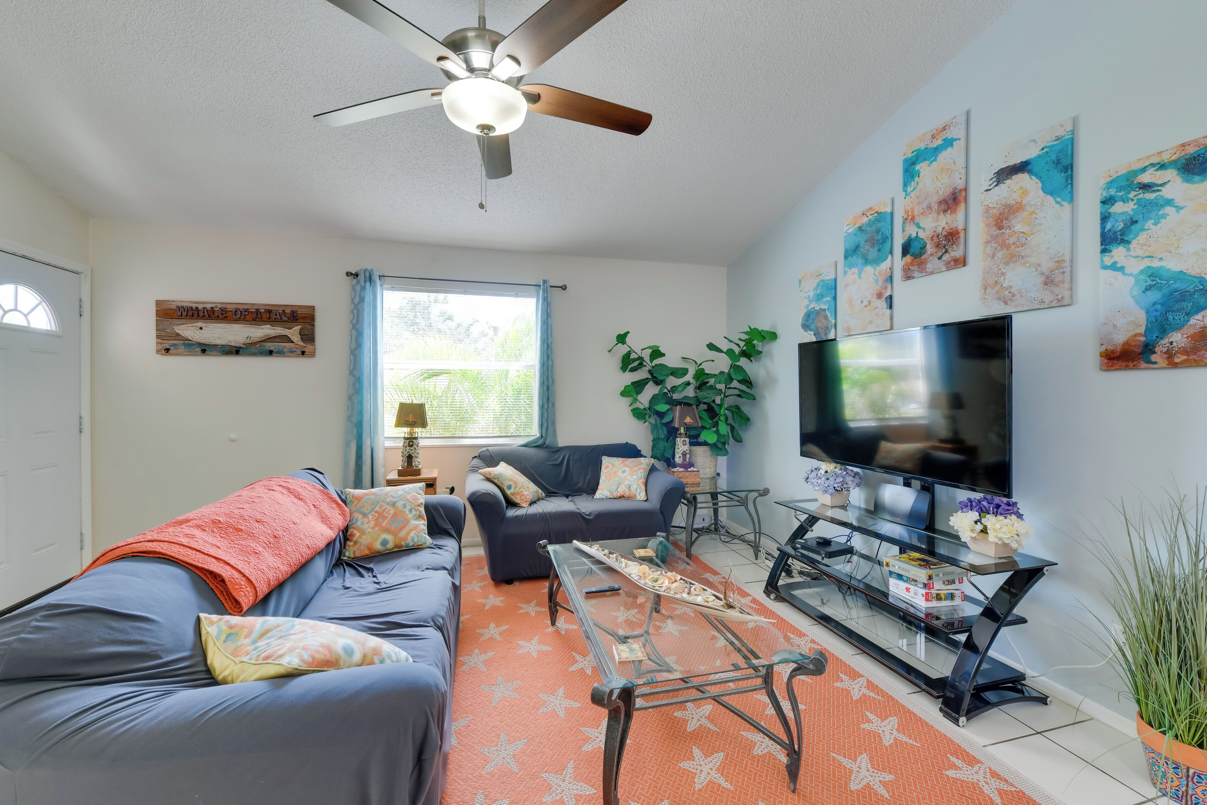 A living room with a ceiling fan, a TV, a sofa, a coffee table, and a potted plant.