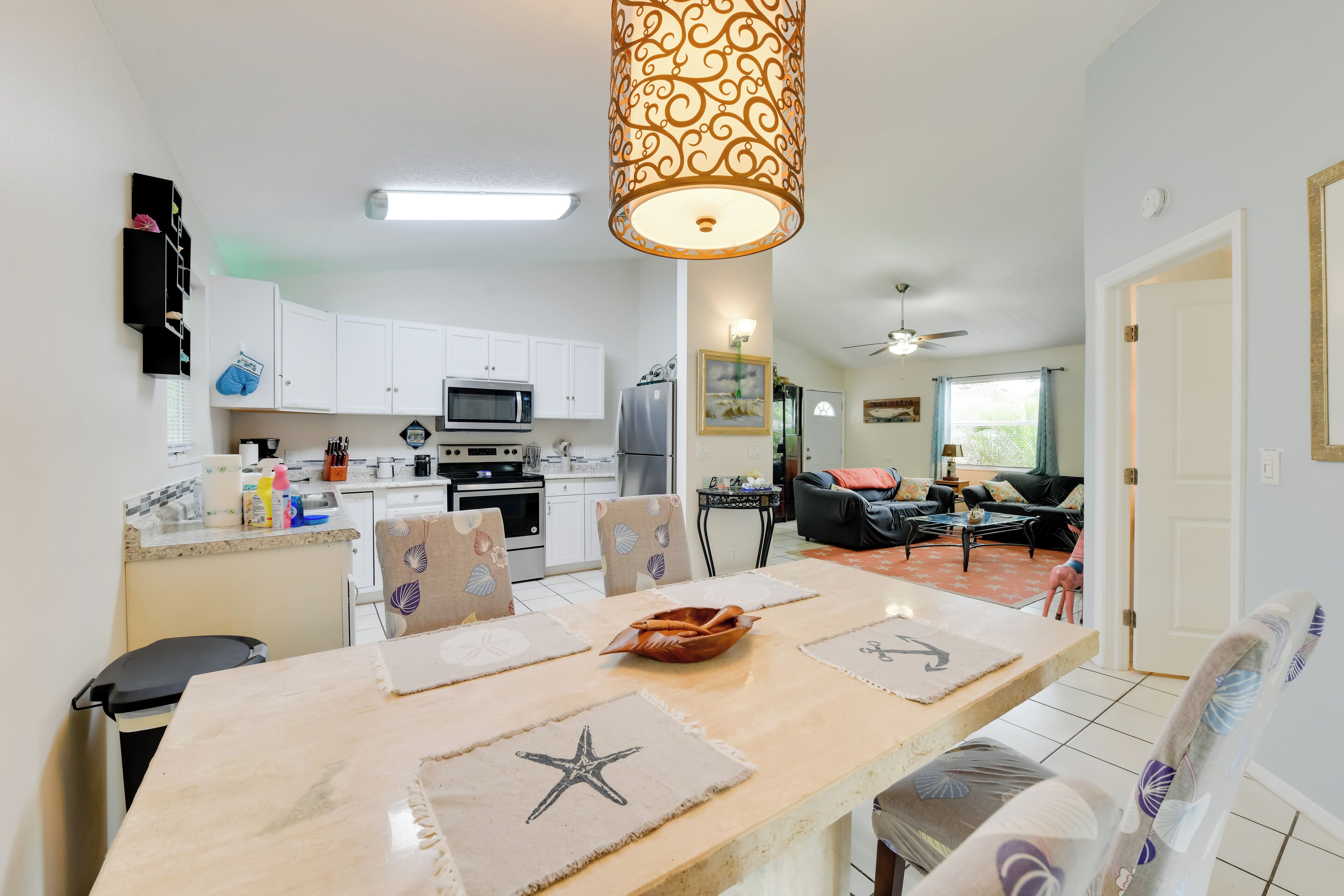 Una cocina moderna con armarios blancos, un microondas y un comedor con posavasos con forma de estrella de mar.
