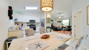 Una cocina moderna con armarios blancos, un microondas y un comedor con posavasos con forma de estrella de mar.