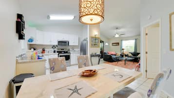 Una cocina moderna con armarios blancos, un microondas y un comedor con posavasos con forma de estrella de mar.