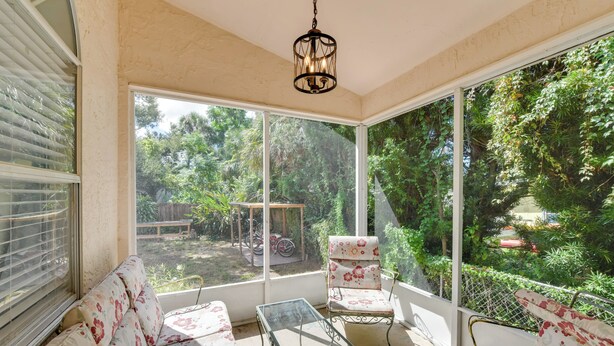 Una habitación iluminada por el sol, con un ventanal grande, un sofá, una silla y una mesa.