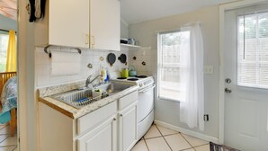 A kitchen with white cabinets, a stove, and a sink.