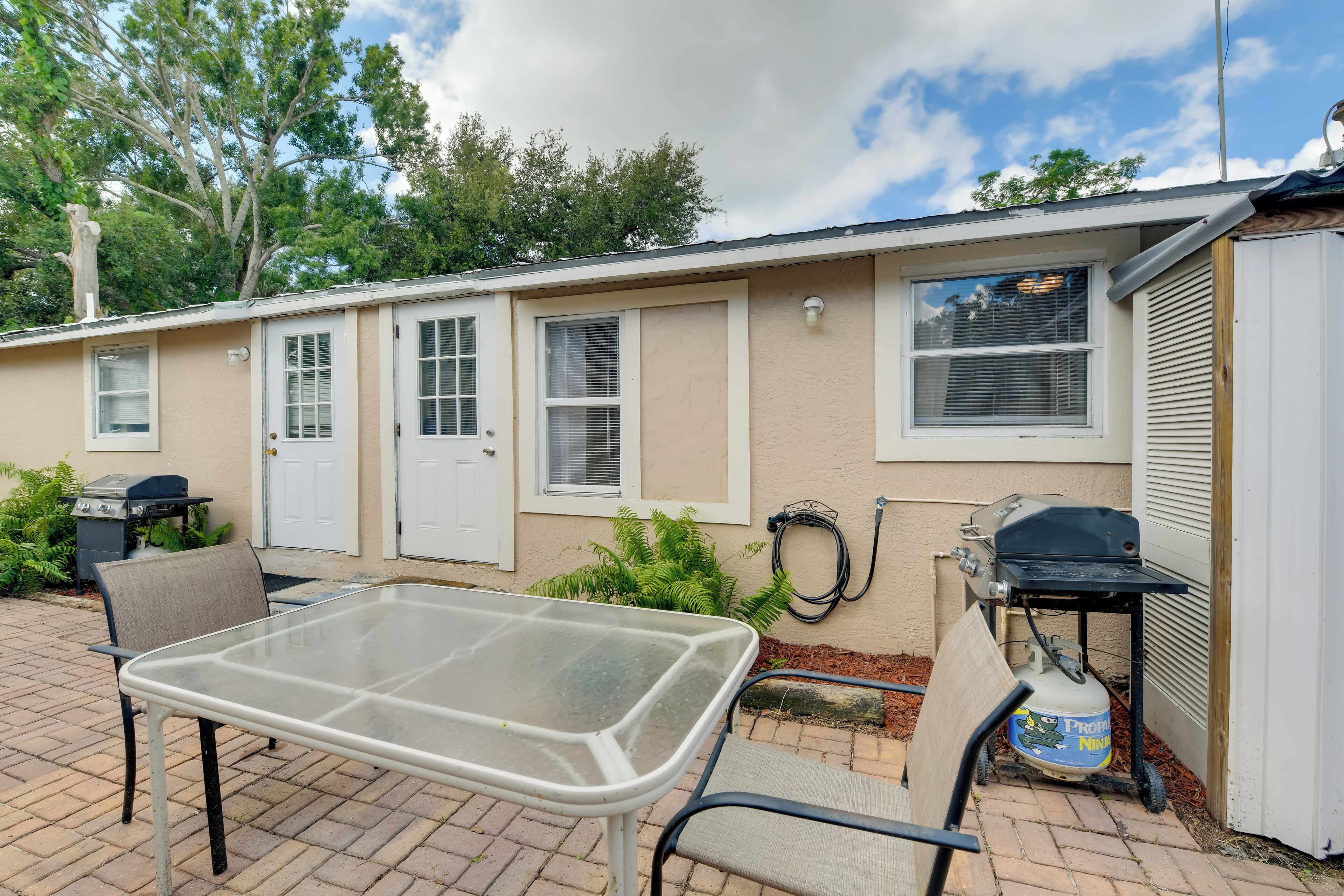 A mobile home with a patio area featuring a grill, a table, and chairs.