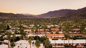 Un barrio residencial con casas, palmeras y montañas al fondo.