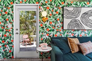 Una habitación con puerta al exterior, una mesita con teléfono y un sofá con cojines.