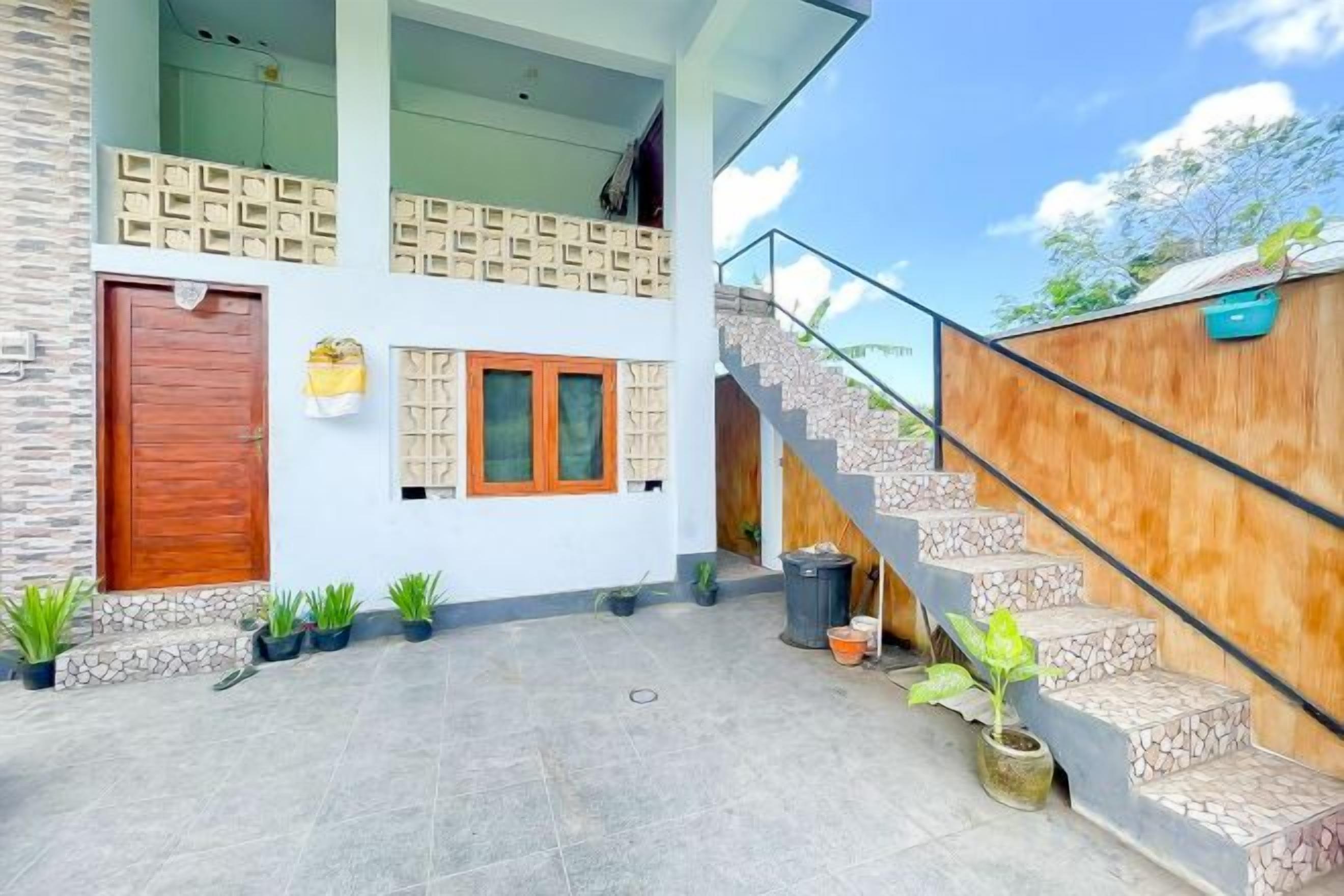 A modern building with a staircase, a wooden door, and potted plants.