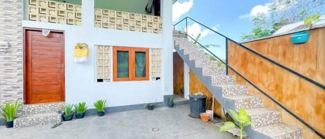 Un edificio moderno con una escalera, una puerta de madera y plantas en macetas.