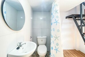 A bathroom with a white sink, a toilet, and a shower curtain with starfish patterns. - Winy House (Bali)