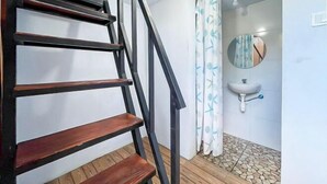 A staircase with wooden steps and black railings, leading to a bathroom with a white sink and a round mirror. - Winy House (Bali)