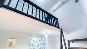 A room with a white ceiling, a black railing, a white curtain with starfish pattern, and a framed picture on the wall. - Winy House (Bali)