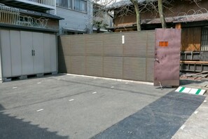 A gated parking area with a metal fence and a large metal gate. - Daisenji Lodge ing (Kyoto)