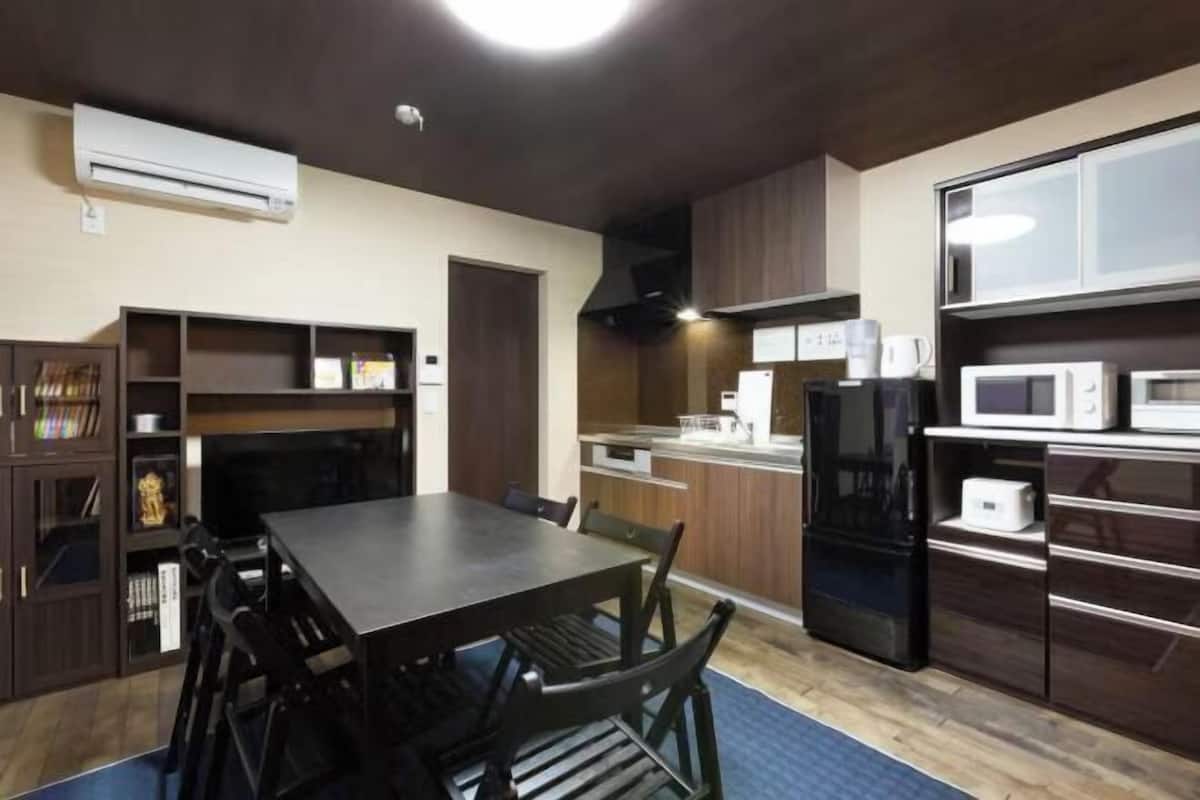 A compact kitchen with a dining table, chairs, a microwave, a coffee maker, and a built-in oven.