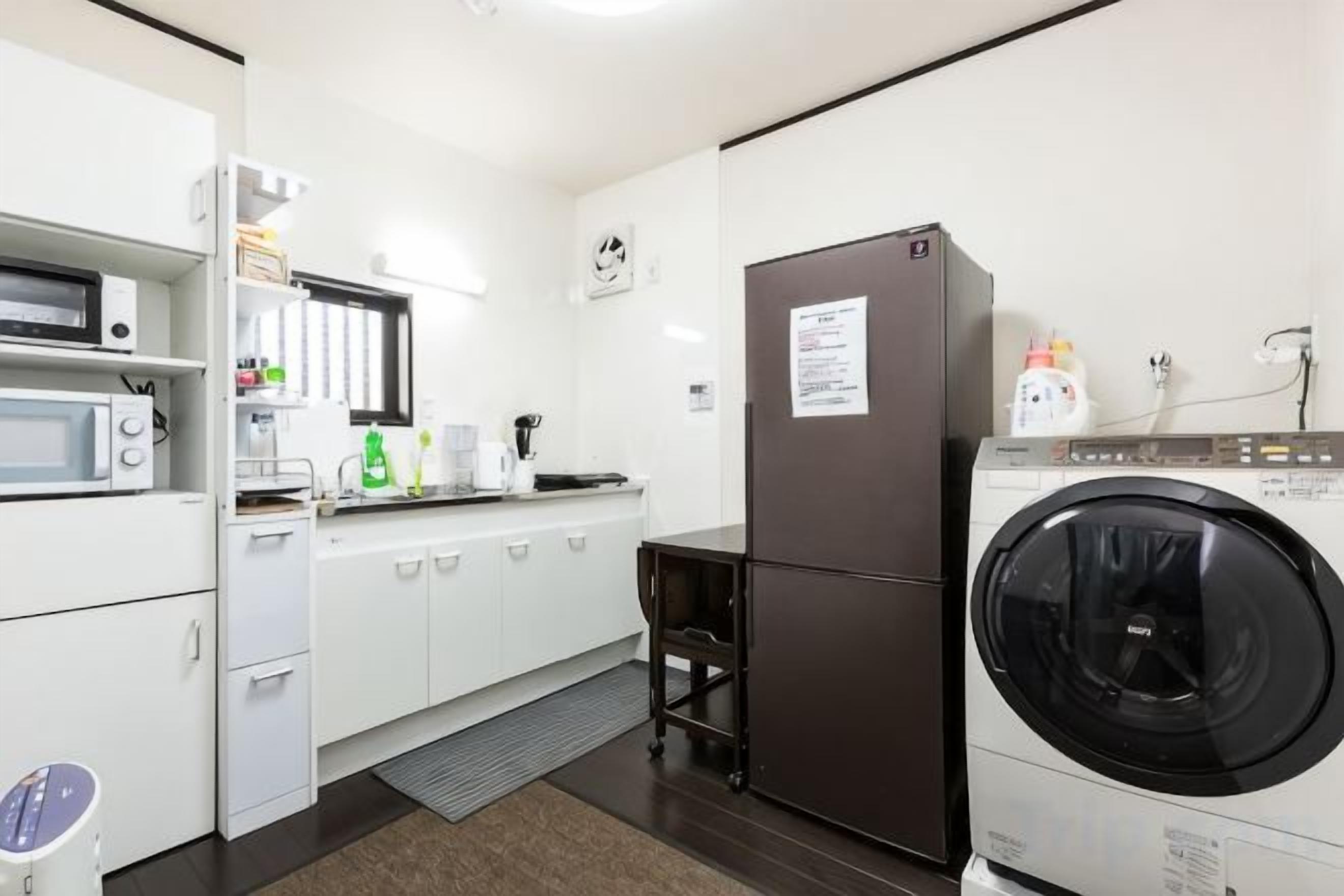 A compact kitchen with a microwave, refrigerator, and washing machine.