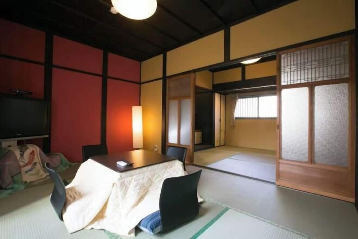 A tatami mat room with a low table, chairs, and sliding doors.