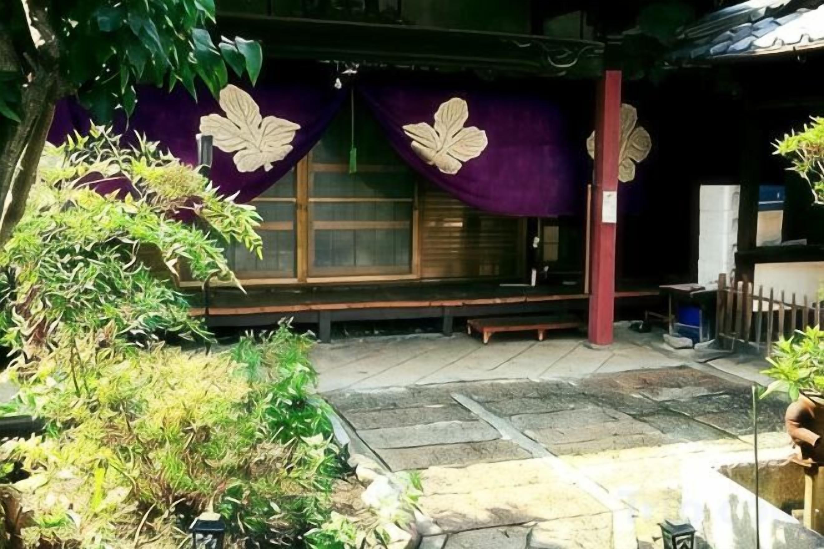 En traditionell japansk byggnad med golv av tatamimattor, en träbänk och en stenlykta.