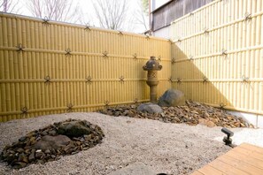 A bamboo fence, a stone water feature, and a gravel area with rocks. - Daisenji Lodge ing (Kyoto)