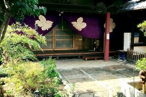 A traditional Japanese building with tatami mats, a wooden bench, and a stone pathway. - Daisenji Lodge ing (Kyoto)