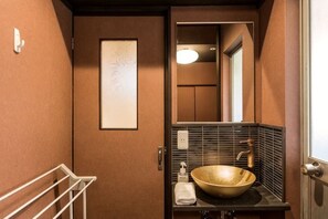 A compact bathroom with a large bowl sink, a towel rack, and a framed artwork on the wall. - Daisenji Lodge ing (Kyoto)