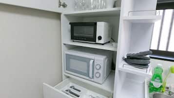 Een keuken met een magnetron, een broodrooster en een lade met bestek.