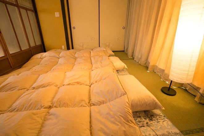 Quarto com cama, luminária de pé e porta japonesa tradicional deslizante.