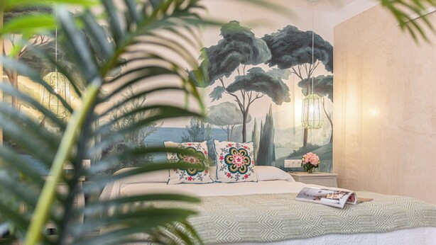 A bedroom with a bed, a nightstand, a magazine, and a painting of trees. - Cathedral Keepers - Exclusive apartment in Jerez (Jerez de la Frontera)