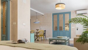 A room with a bed, a dining table with chairs, a blue door, and a hanging light fixture. - Cathedral Keepers - Exclusive apartment in Jerez (Jerez de la Frontera)