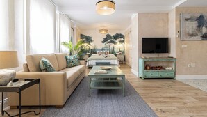 A modern living room with a sofa, coffee table, and a TV. - Cathedral Keepers - Exclusive apartment in Jerez (Jerez de la Frontera)