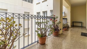 A corridor with potted plants, a metal railing, and a bench. - Cathedral Keepers - Exclusive apartment in Jerez (Jerez de la Frontera)