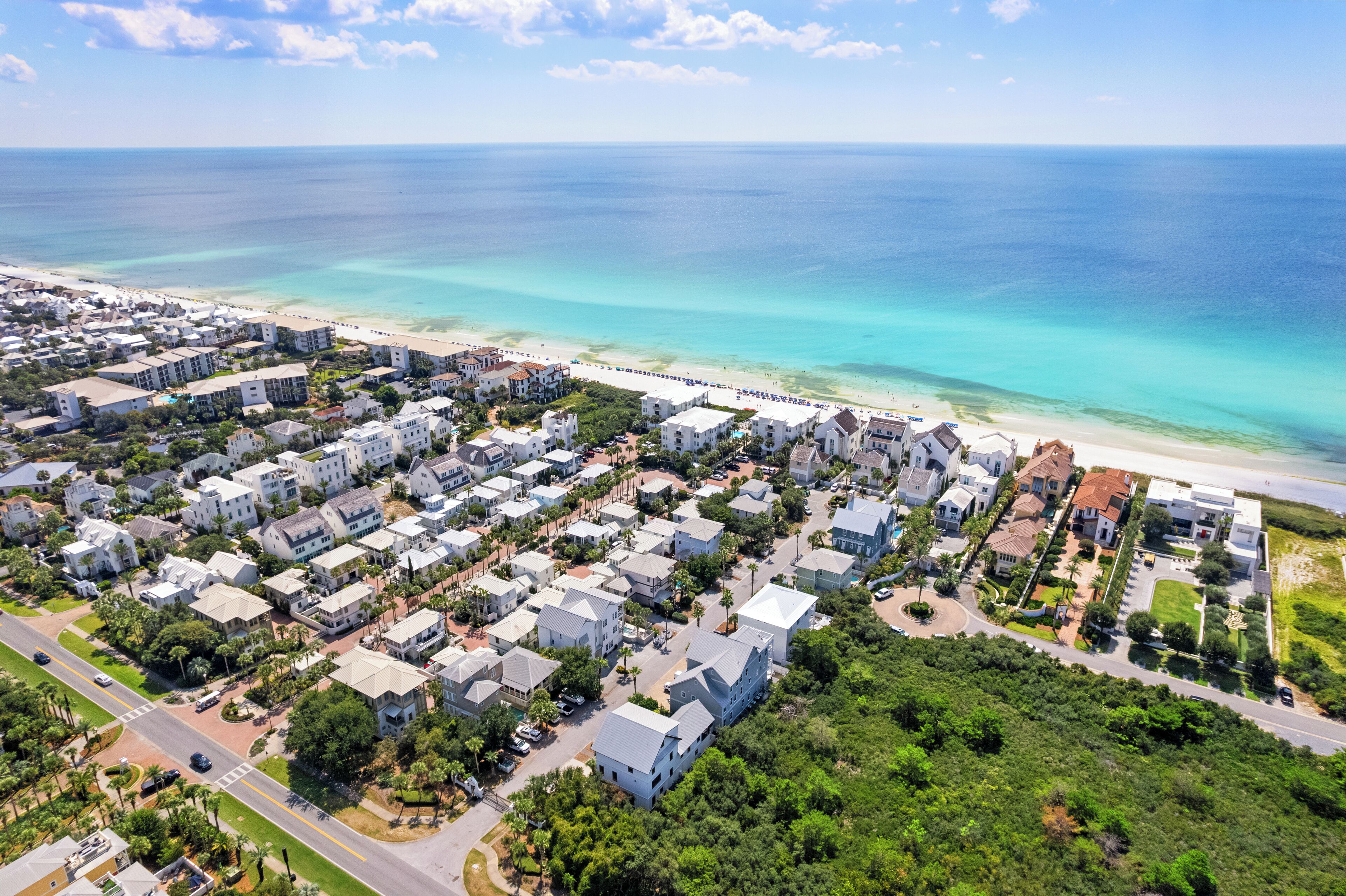 An aerial view of a coastal residential area with houses, roads, and a beach.