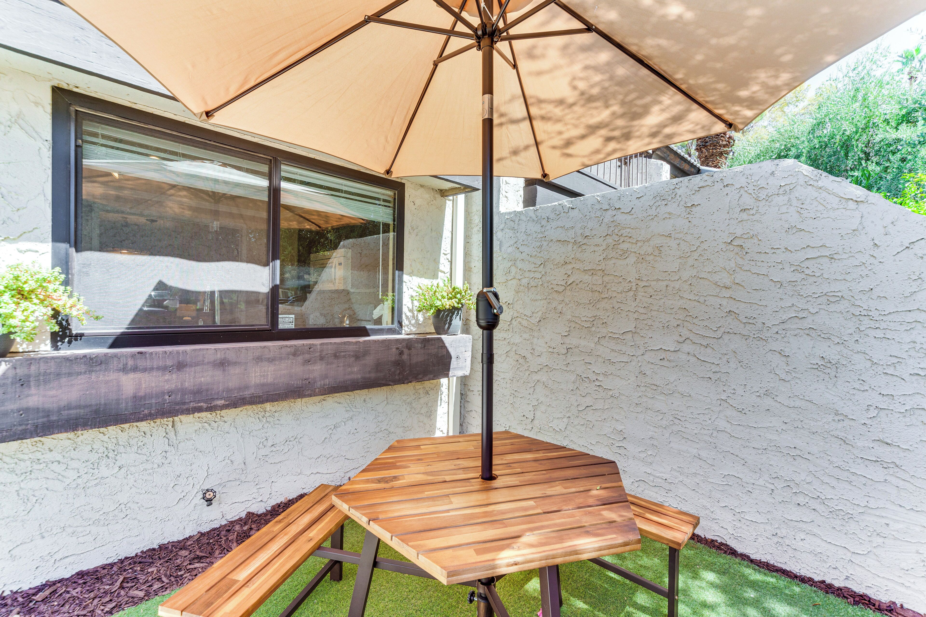 Una mesa de madera con paraguas, una ventana y una pared blanca con textura.