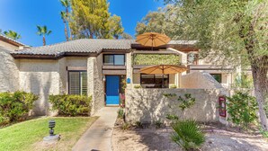 A two-story house with a stone facade, a blue door, and a small garden with a pathway leading to the entrance. - Resort-style Palm Springs Townhome w/ Pool Access (Palm Springs)