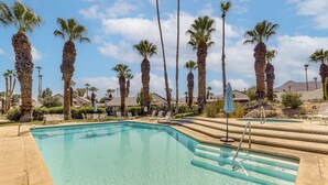 A clear swimming pool with steps leading into it, surrounded by palm trees and lounge chairs. - Resort-style Palm Springs Townhome w/ Pool Access (Palm Springs)