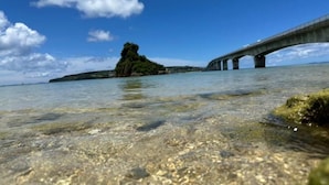 A clear view of a bridge over water with a rocky island in the background. - STARS (Kunigami District)
