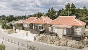 A row of modern houses with red roofs, stone foundations, and a paved driveway. - STARS (Kunigami District)