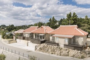 A row of modern houses with red roofs, stone foundations, and a paved driveway. - STARS (Kunigami District)