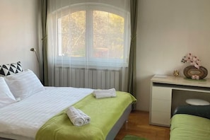 A neatly arranged bedroom with a bed, a desk, and a window with curtains.