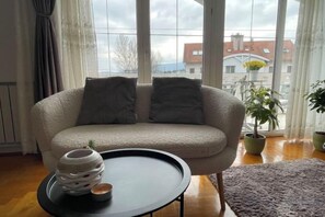 Un soggiorno con un divano, un tavolino e una finestra vista edifici.