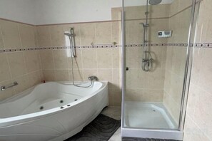 Un bagno con vasca, doccia e box doccia in vetro.