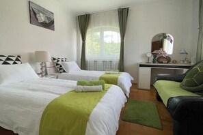 Habitación de hotel con dos camas, un escritorio, una silla, un espejo y una ventana con cortinas.