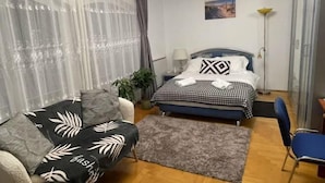 A bedroom with a bed, a chair, a lamp, and a window with curtains. - Meszko Park House Budapest (Budapest)