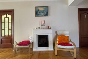 A room with a fireplace, two chairs, a painting, and a door. - Meszko Park House Budapest (Budapest)