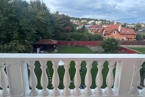 A balcony with a white balustrade overlooking a residential area with houses and greenery. - Meszko Park House Budapest (Budapest)