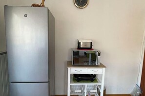 A kitchen with a refrigerator, microwave, and a small white cabinet with drawers. - Meszko Park House Budapest (Budapest)
