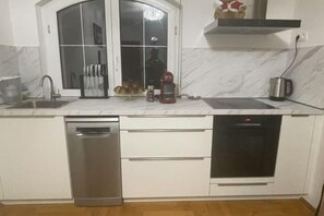 A kitchen with a dishwasher, oven, and a window with a view. - Meszko Park House Budapest (Budapest)
