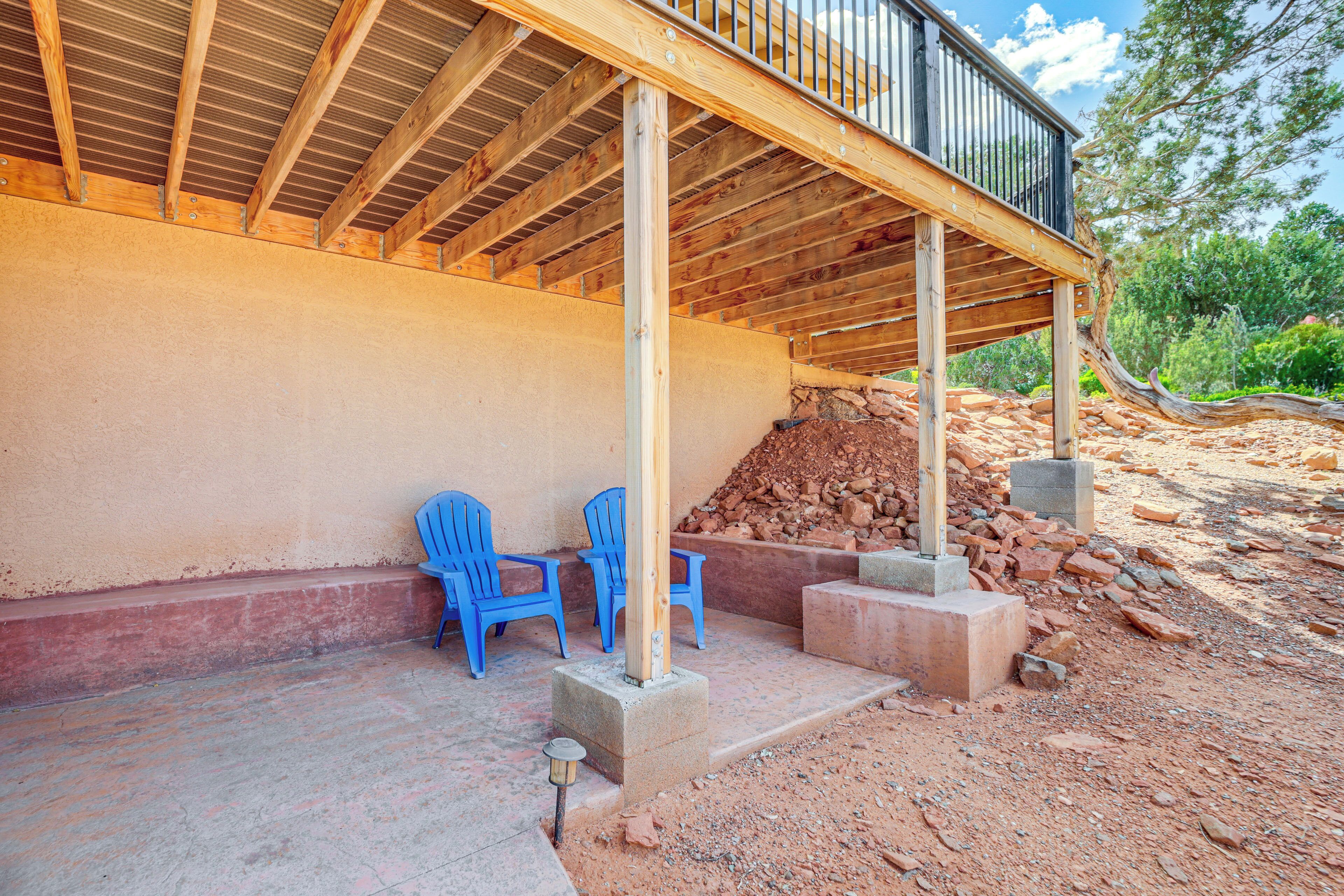 A covered outdoor area with a wooden deck, blue plastic chairs, and a pile of construction materials.